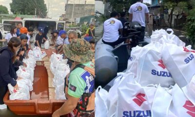 Volunteers and rescue teams use Suzuki-powered boats to deliver white relief bags labeled with the Suzuki logo to flood-affected residents in a submerged neighborhood.