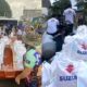 Volunteers and rescue teams use Suzuki-powered boats to deliver white relief bags labeled with the Suzuki logo to flood-affected residents in a submerged neighborhood.
