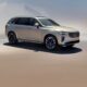 A gold Volvo XC90 Plug-in Hybrid SUV parked under soft daylight, showcasing its modern design and signature Thor’s Hammer LED headlights.