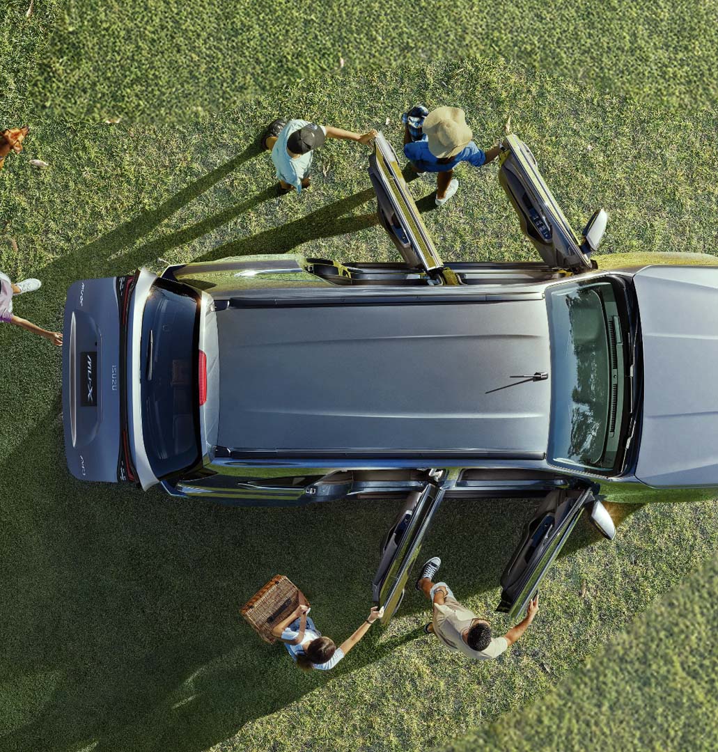Aerial view of an Isuzu mu-X parked on grass with passengers opening the doors, ready for an outdoor trip.