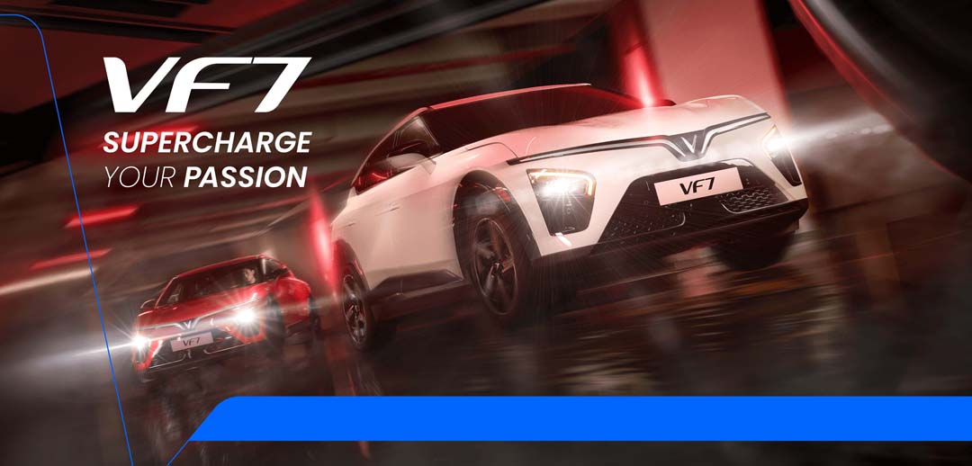 Two VinFast VF 7 electric SUVs—one in red, one in white—racing through a sleek, futuristic tunnel under dramatic red lighting, with motion blur emphasizing speed and power.