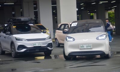 A lineup of electric vehicles, including a BYD crossover and a Wuling compact EV, parked in an urban lot during a Philippine EV industry event.