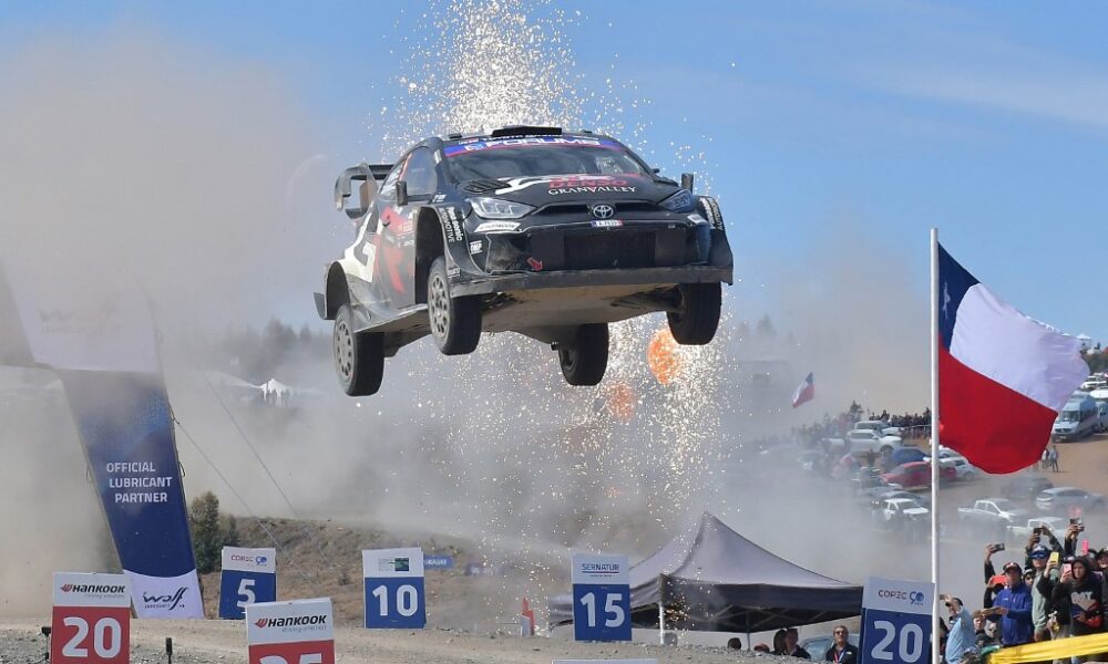Sebastien Ogier’s Toyota Yaris Rally1 car airborne during a jump at the Rally of Chile, with sparks flying and the Chilean flag in the background.