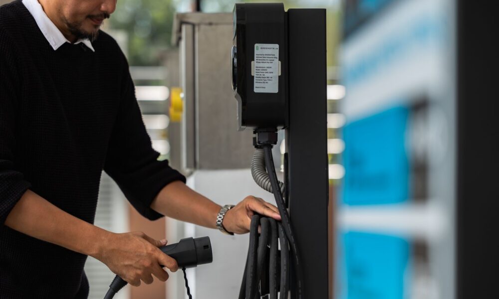 A man prepares an electric vehicle charging cable at an ACMobility charging station in the Philippines.