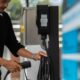 A man prepares an electric vehicle charging cable at an ACMobility charging station in the Philippines.