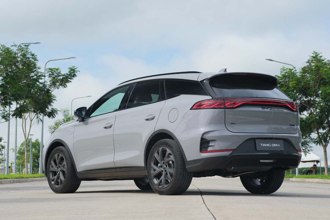 Rear view of the new BYD Tang DM-i plug-in hybrid SUV in silver, parked outdoors with trees and lamp posts in the background.