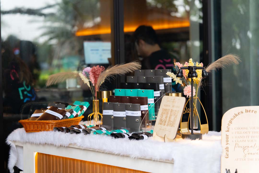 A display of Lynk & Co personalized giveaways, including passport holders and key holders, arranged on a decorated table at the Lynk Ups event.