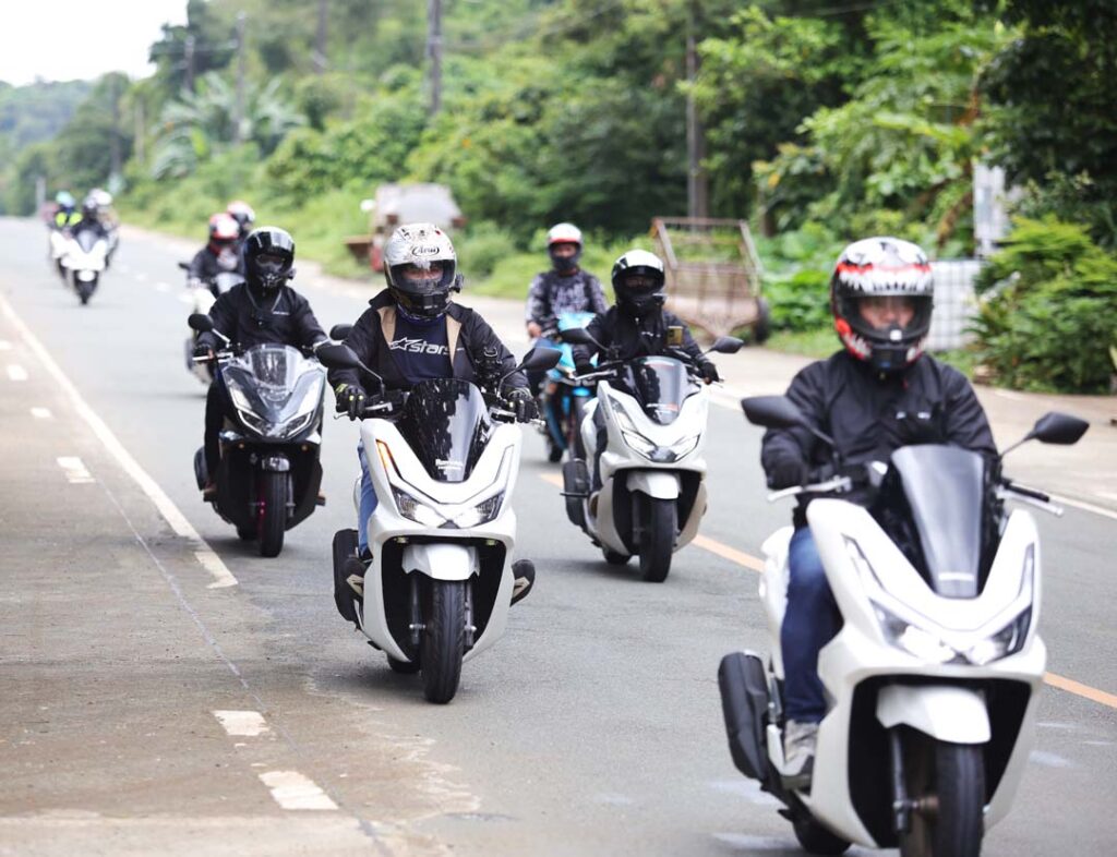 A group of riders on Honda PCX160 scooters cruise together along a countryside road in Tanay during the PCXceptional Ride event.