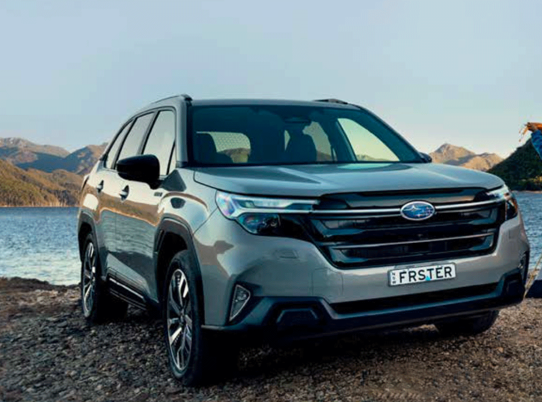 Front view of the 2026 Subaru Forester Hybrid parked by a lake with mountain scenery in the background.