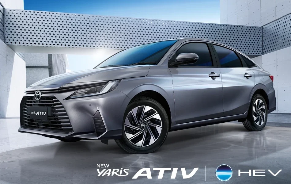 A silver Toyota Yaris Ativ HEV parked in a modern, minimalist setting with metallic walls and geometric patterns, showcasing its sleek design and alloy wheels.