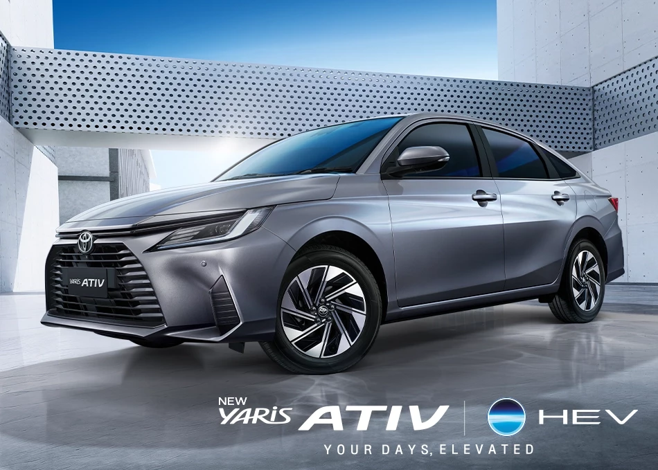 A silver Toyota Yaris Ativ HEV parked in a modern, minimalist setting with metallic walls and geometric patterns, showcasing its sleek design and alloy wheels.