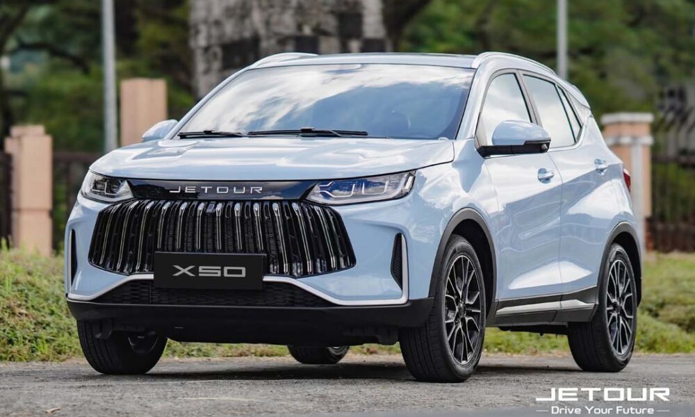 Front view of a white Jetour X50 SUV parked outdoors, showcasing its bold grille and modern design.