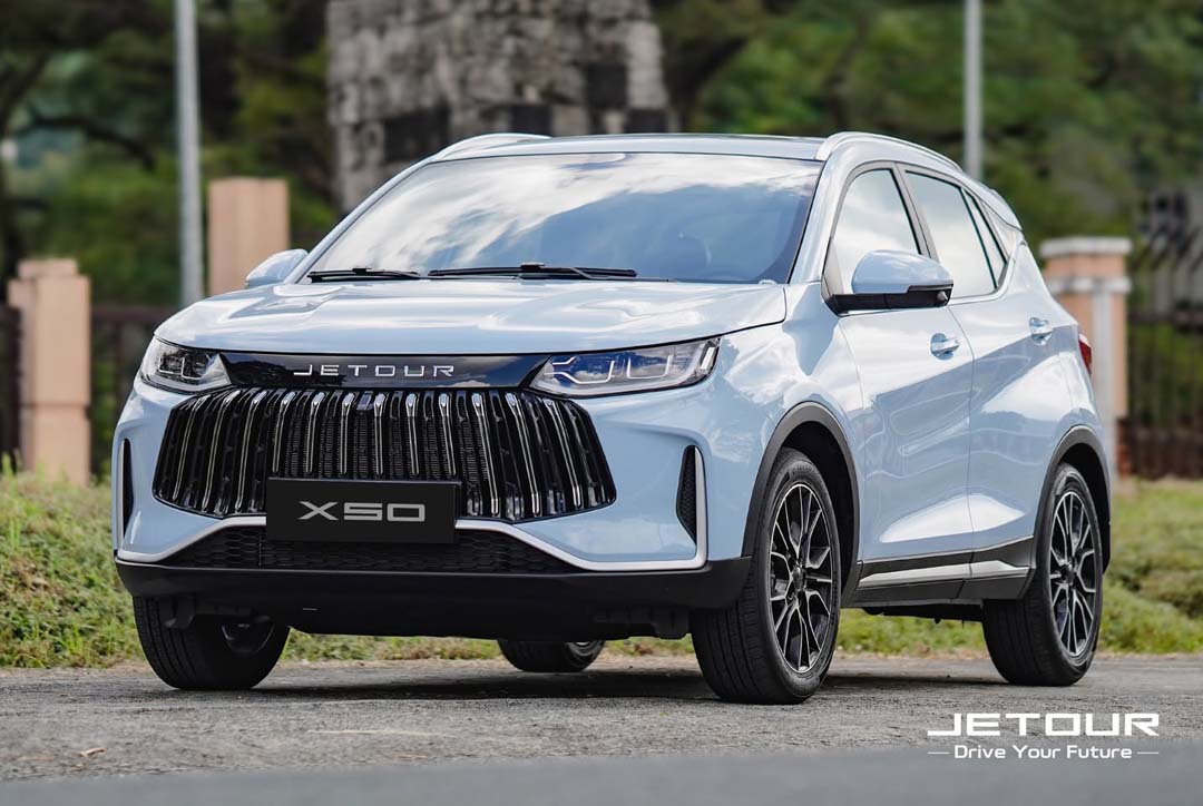 Front view of a white Jetour X50 SUV parked outdoors, showcasing its bold grille and modern design.