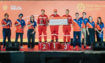 Shell Mekaniko League 2025 champions stand on the podium with a giant check and trophy, joined by Shell executives and organizers on stage.