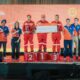 Shell Mekaniko League 2025 champions stand on the podium with a giant check and trophy, joined by Shell executives and organizers on stage.
