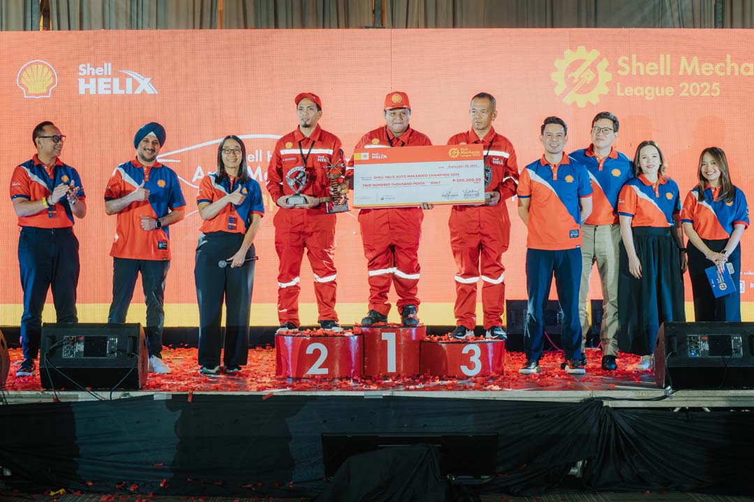 Shell Mekaniko League 2025 champions stand on the podium with a giant check and trophy, joined by Shell executives and organizers on stage.