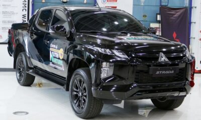 A black Mitsubishi Strada Athlete pickup on display at the MMPC showroom, bearing the UPLB DUNONG Nutri-Nurture Project logo on its doors.