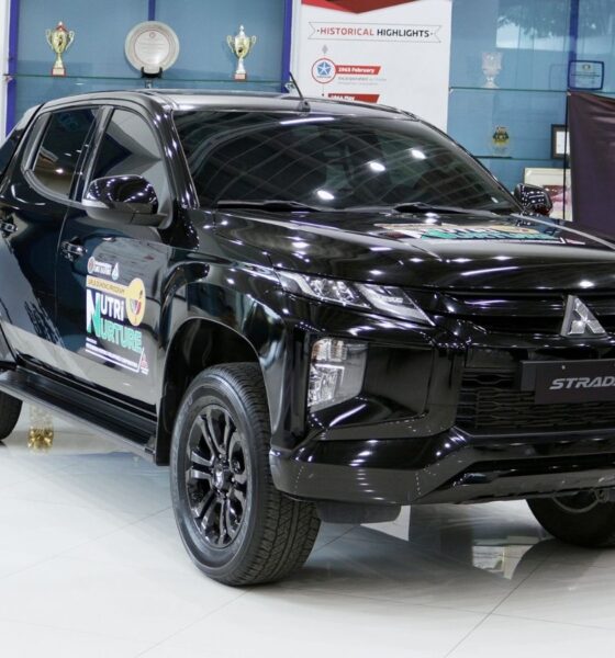A black Mitsubishi Strada Athlete pickup on display at the MMPC showroom, bearing the UPLB DUNONG Nutri-Nurture Project logo on its doors.